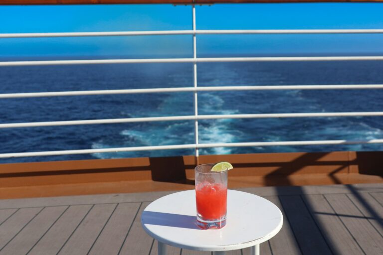 cocktail sitting on a white table on the deck of a cruise boat