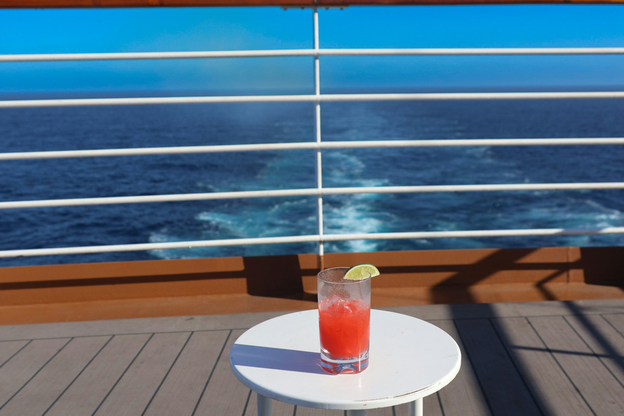 cocktail sitting on a white table on the deck of a cruise boat